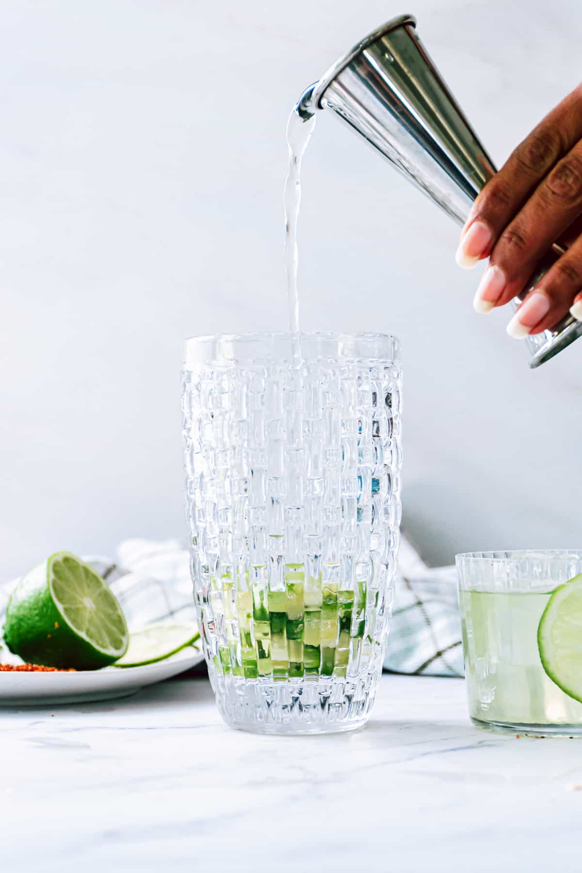 pouring tequila in with cucumber and jalapeno