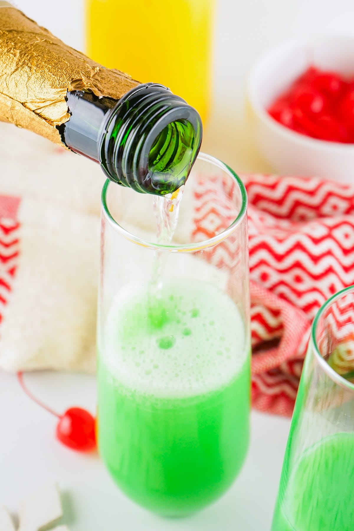 Pouring champagne over orange juice mixture.